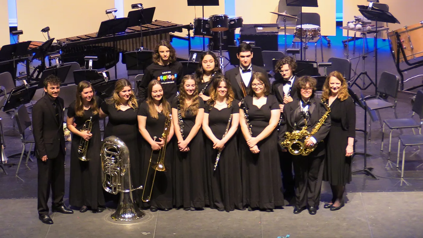 South Lyon concert-band students smiling together in a group onstage