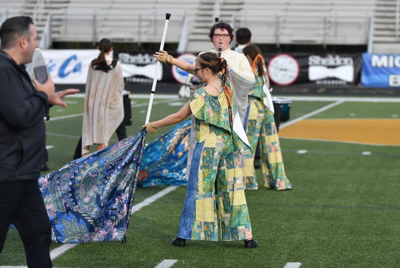 South Lyon Color Guard members performing with flags on the football field